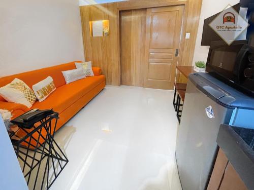 a living room with an orange couch in front of a door at GTC Apartelle in Tacloban
