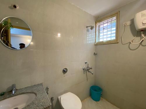 a bathroom with a sink and a toilet and a mirror at Apricot BH6 in Marmagao