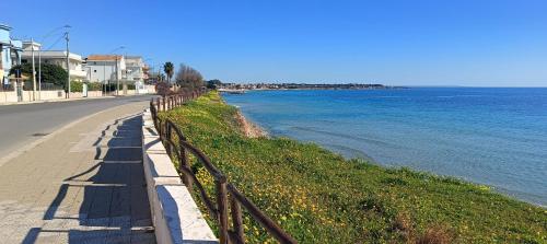 a road with a fence next to the water at Krizia Mare in Avola