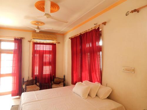 1 dormitorio con cortinas rojas y 1 cama con 2 almohadas en Vishal Villa, en Jaipur