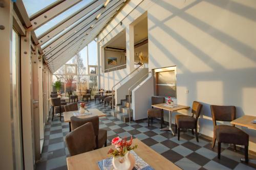 a restaurant with tables and chairs and a checkered floor at Inselhotel kleiner Bodden in Buschvitz