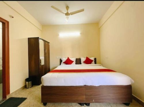 um quarto com uma cama grande e almofadas vermelhas em Sai Manyata Inn, Bangalore em Bangalore