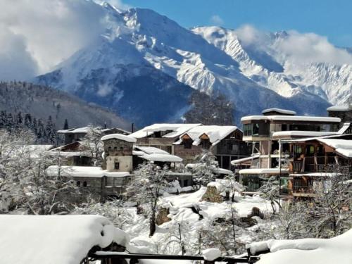a village covered in snow with a mountain in the background at Galasha in Mestia