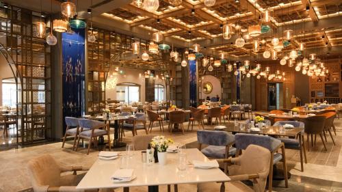a dining room with tables and chairs and chandeliers at Kempinski Hotel The Dome Belek in Belek