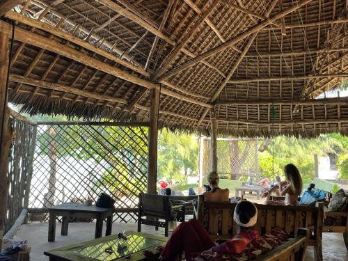 un groupe de personnes assises dans un pavillon dans l'établissement Sazani Beach Lodge and Tidal Lounge, à Nungwi