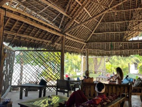 a group of people sitting in a pavilion at Sazani Beach Lodge and Tidal Lounge in Nungwi