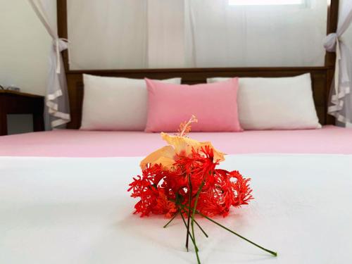 a bouquet of red flowers sitting on a bed at Era Holiday House in Mirissa