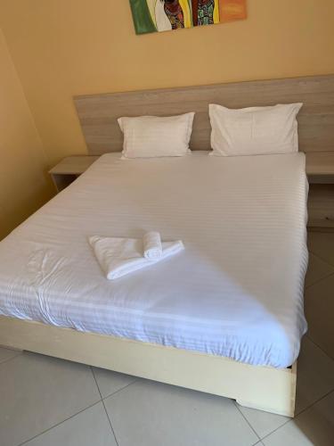 a bed with white sheets and two towels on it at JUBILEE EXECUTIVE LODGE in Lusaka