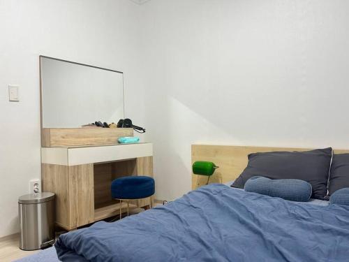 1 dormitorio con cama azul y espejo en Homey inn Juno, en Suwon