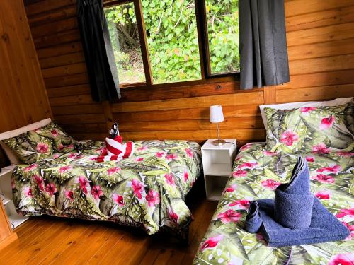 two beds in a room with wooden walls and windows at Muri Vista Villas in Rarotonga