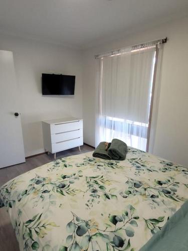 a bedroom with a bed and a dresser and a window at The Sturt Stay in Mulwala