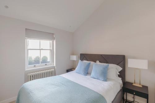 1 dormitorio blanco con 1 cama grande con almohadas azules en Parkside House - Regent's Park - by Frankie Says, en Londres