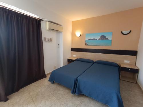1 dormitorio con 1 cama con manta azul en Hostal Horizonte, en San Antonio