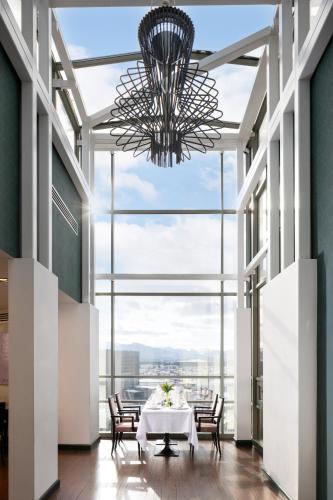 a dining room with a table and chairs and a chandelier at Hotel Golden Tulip Ana Tower Sibiu in Sibiu