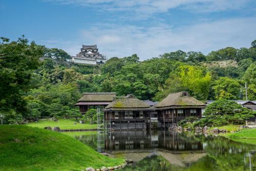 a group of buildings on the water with a building in the background at Hotel Sunroute Hikone in Hikone