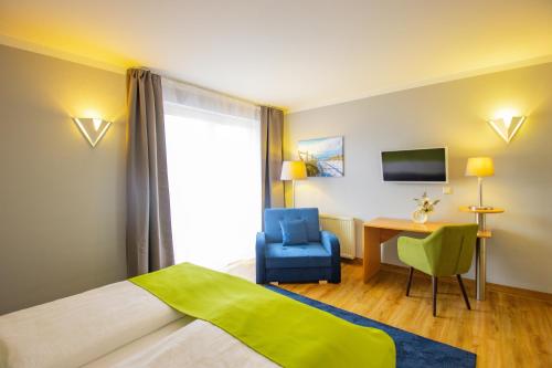 a hotel room with a bed and a chair and a desk at Inselhotel kleiner Bodden in Buschvitz