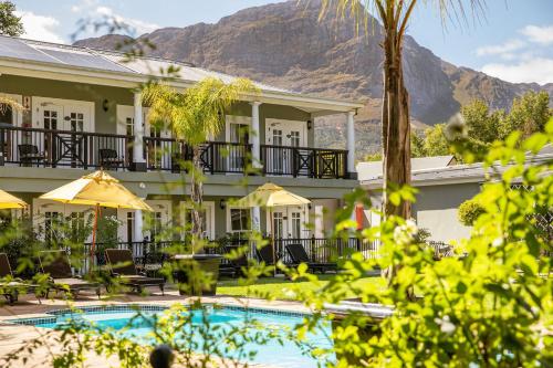 un hôtel avec une piscine et des montagnes en arrière-plan dans l'établissement Protea Hotel by Marriott Franschhoek, à Franschhoek