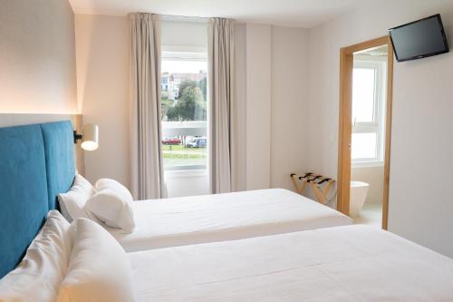una camera d'albergo con due letti e una finestra di Hotel Parking Miradoiro de Belvís a Santiago de Compostela