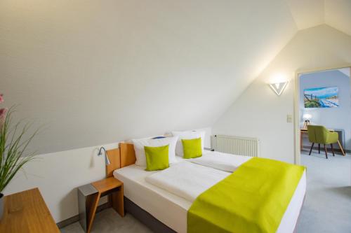 a bedroom with a large white bed with yellow pillows at Inselhotel kleiner Bodden in Buschvitz
