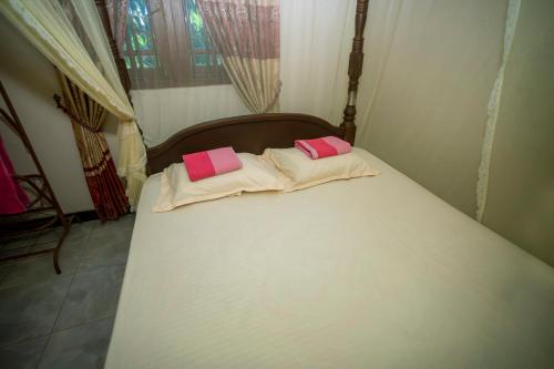 a large white bed with two pink pillows on it at Sajini Villa in Weligama
