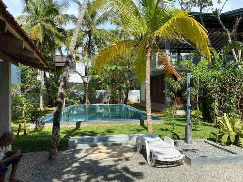 a resort with a swimming pool and palm trees at moments hotel & restaurant in Hikkaduwa