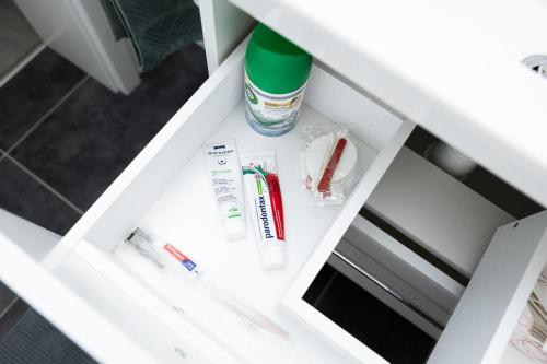 uma gaveta num armário branco com escovas de dentes e pasta de dentes em Schöne Wohnung am See mit Wi-Fi & Netflix em Bielefeld