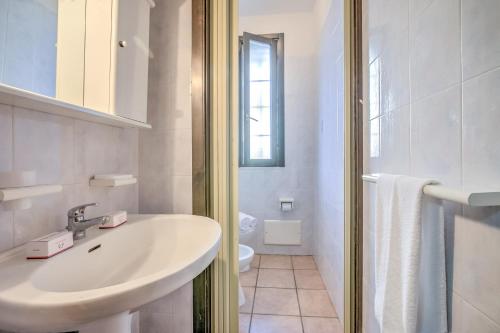 Baño blanco con lavabo y aseo en Villetta Dei Pini With Pool in Residence - Happy Rentals, en Melendugno