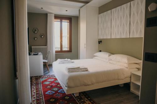 Naboo Verona Luxury Suites في فيرونا: غرفة نوم مع سرير أبيض كبير مع سجادة حمراء