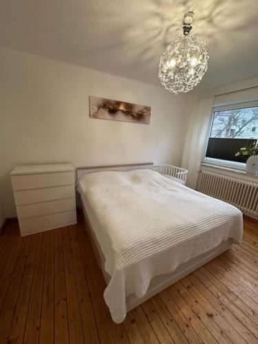 a white bedroom with a bed and a chandelier at Wunderschöne Altbauwohnung in Bremerhaven