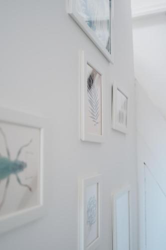 a row of framed photographs on a white wall at North Sea's White Shelter - 4 personnes in Koksijde