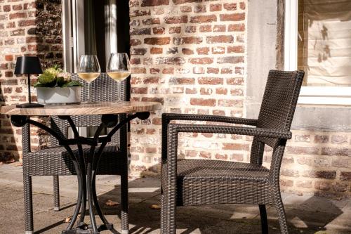 two chairs and a table with wine glasses on a patio at Van der Valk Hotel Kasteel Terworm in Heerlen