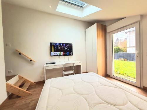 een slaapkamer met een bed, een bureau en een televisie bij Chambre paisible chez l'habitant en rez de chaussée avec salle d'eau 10 min gare et centre ville in Évreux