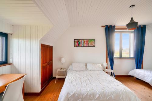 - une chambre avec un lit blanc et des rideaux bleus dans l'établissement 100m de la plage - maison pour 10 personnes, à Penmarcʼh
