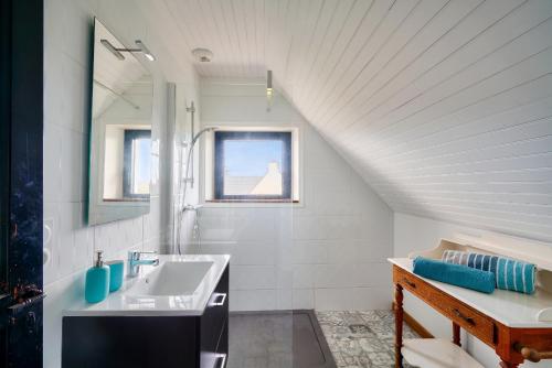 une salle de bain blanche avec un lavabo et un miroir dans l'établissement 100m de la plage - maison pour 10 personnes, à Penmarcʼh