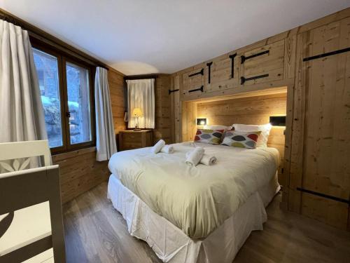 a bedroom with a large white bed with wooden walls at Chalet Des Encombres - Pièces 314 in Saint-Martin-de-Belleville