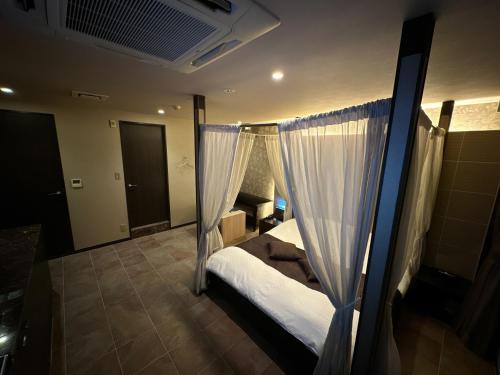 een slaapkamer met een bed en gordijnen in een kamer bij HOTEL felice in Toyonaka