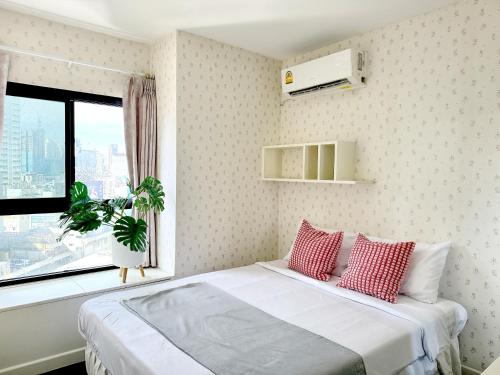 - une chambre avec un lit doté d'oreillers rouges et une fenêtre dans l'établissement Grand Diamond Condominium, à Bangkok