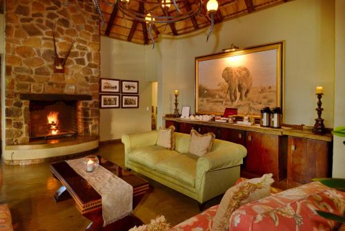 een woonkamer met een bank en een open haard bij Motswiri Private Safari Lodge in Madikwe Wildreservaat