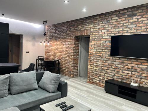 Una sala de estar con un sofá y una pared de ladrillos. en Raciborska Royal Apartment - miejsce parkingowe na parkingu strzeżonym, en Gliwice