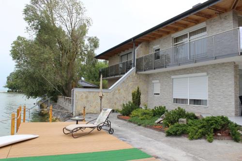 ein Haus mit einer Terrasse mit einem Stuhl darauf in der Unterkunft Parton Villa Apartments in Fonyód