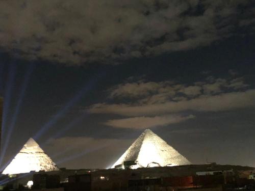 two pyramids are lit up in the sky at night at King Of Pyramids Hotel in Cairo