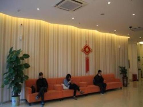 three people sitting on a couch in a room at Yulin Jintone Hotel Wenhua Square Branch in Yulin