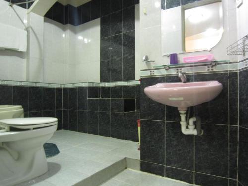 a bathroom with a pink sink and a toilet at Timi Hotel in Ho Chi Minh City