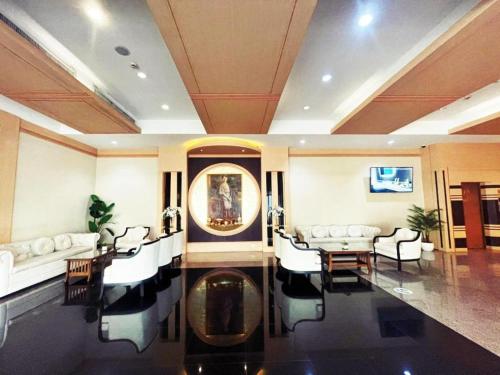 a living room with white furniture and a table and chairs at Valaya Hotel Pathumthani in Pathum Thani