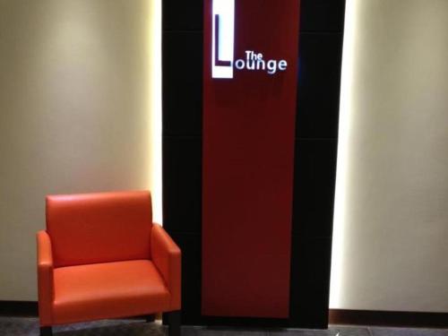 uma cadeira laranja sentada em frente a uma placa em The Grande Suites em Surigao