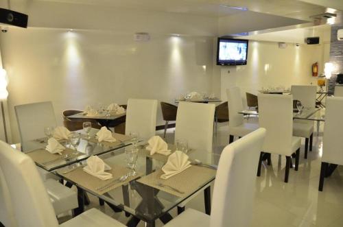 a dining room with a glass table and white chairs at The Grande Suites in Surigao