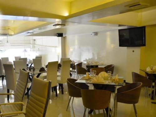 uma sala de jantar com mesas e cadeiras e uma televisão em The Grande Suites em Surigao