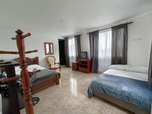 1 dormitorio con 2 camas y TV. en Hotel Campestre Cafetal - Quindio - EJE CAFETERO, en Chorro Seco