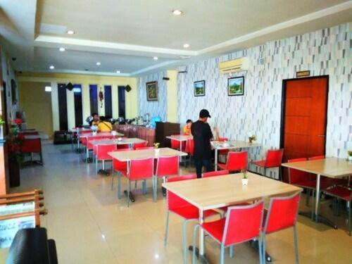 Parma City Hotel في Palas 2: غرفة طعام مع طاولات وكراسي حمراء وشخص