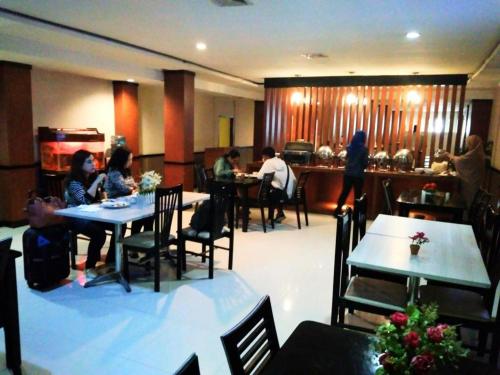 um grupo de pessoas sentadas em mesas em um restaurante em Hotel Parma Pekanbaru em Pekanbaru